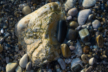 pebble stones on the sea beach, the rolling waves of the sea with foam