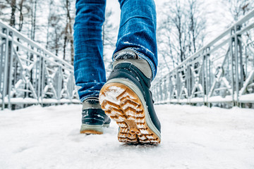 Fototapeta premium Man's legs in boots walking in the snow