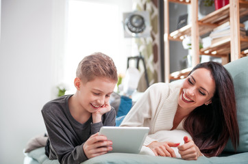 Mom and son using tablet together on sofa at home