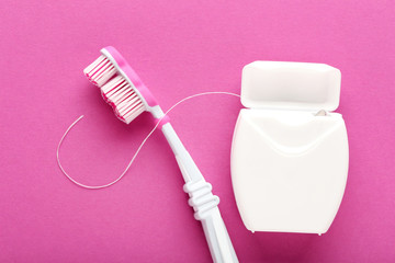 Toothbrush with tooth thread on pink background