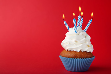 Tasty cupcake with candles on red background