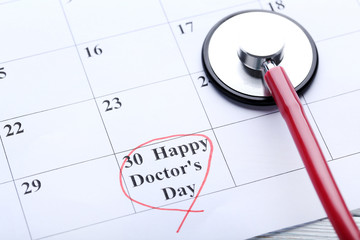 Inscription Happy Doctors Day with stethoscope on march calendar