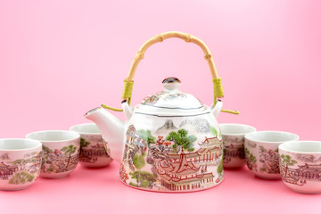 Teapot with cups on a pink background.