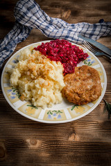 Pork cutlet with minced meat served with boiled potatoes and beetroot.