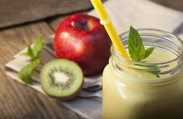 Smoothie in glass jar on rustik wood. Green healthy beverage and fresh fruit