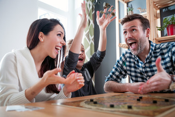 Family playing board game at home, boy throwing elements after winning