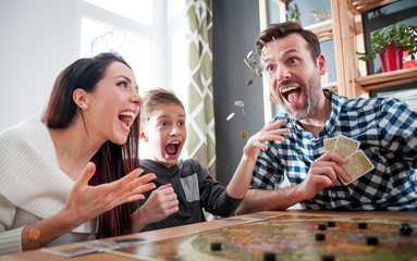 Family playing board game at home, boy throwing elements after winning