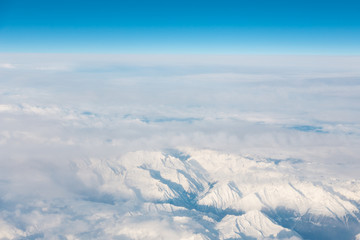 aerial view on the snow capped alpes from airplane blue sky and horizon