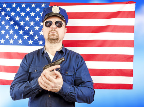 A male policeman holding a gun over a US flag satin - a studio shoot