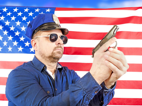 A male policeman holding a gun over a US flag satin - a studio shoot