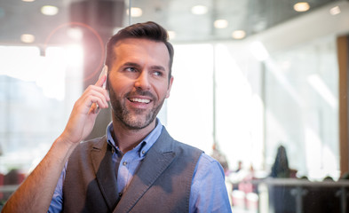 Handsome businessman talking phone in modern indoors, success in business