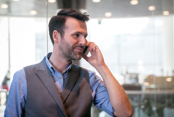 Handsome businessman talking phone in modern indoors, success in business