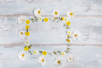 Obraz premium A bouquet of white flowers cosmea or cosmos with ribbon on white boards. Garden yellow flowers over handmade wooden table background. Backdrop with copy space.