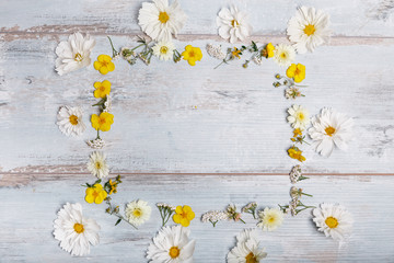 Obraz premium A bouquet of white flowers cosmea or cosmos with ribbon on white boards. Garden yellow flowers over handmade wooden table background. Backdrop with copy space.