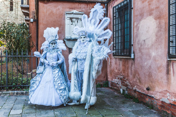 Fototapeta na wymiar VENICE, ITALY - FEBRUARY 10 2018: Pair of white and azure colored carnival masks inside a small courtyard