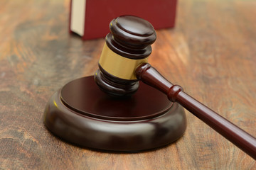 Wooden Gavel and stand with law book in the background