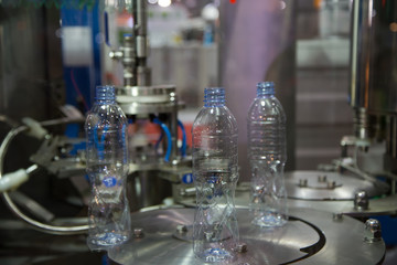 Empty plastic bottle on bottle filling and capping machine. Industrial manufacturing