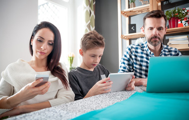 Family with laptop, tablet and smartphone, everyone using digital devices