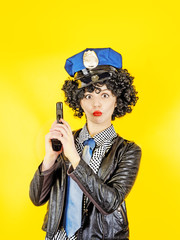 Beautiful woman holding a gun - Super cops, portrait on a yellow background