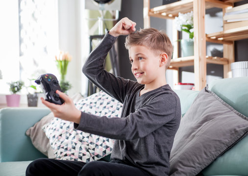 Excited young boy playing game on the console at home