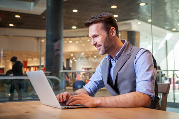 Confident businessman using laptop in modern interior