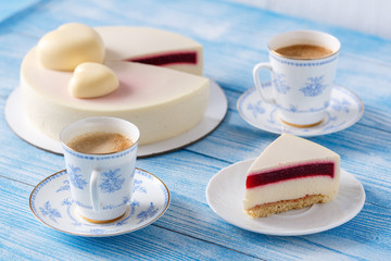 Trendy mousse cake. Slice of cake on a plate. Cup of coffee. Wooden background.