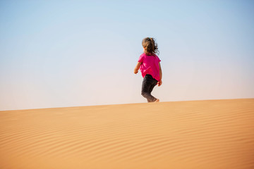 Cute little girl playing on the desert with sand