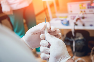 Proctologist holding an anoscope against a proctological chair.