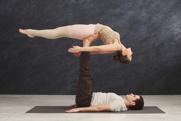 Young couple practicing acroyoga on mat together