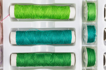 spools and bobbins of sewing threads in shades of green