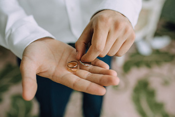 Fototapeta premium A man holds in his hands on the palms of the wedding gold rings. Close-up