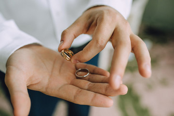 A man holds in his hands on the palms of the wedding gold rings. Close-up