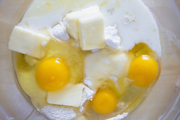 a set of products for dough eggs, butter, flour, milk. all in a transparent bowl