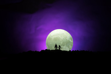 Fototapeta na wymiar Amazing love scene. Silhouettes of young romantic couple standing under the moon light