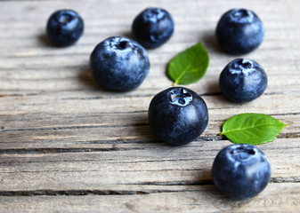 Fresh ripe blueberries with green leaves on rustic wooden table.Bilberry border.Flat lay,top view,selective focus.