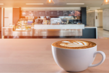white coffee cup on wooden table with coffee bar background