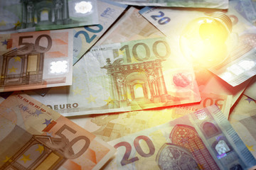Glowing light bulb on a background of money