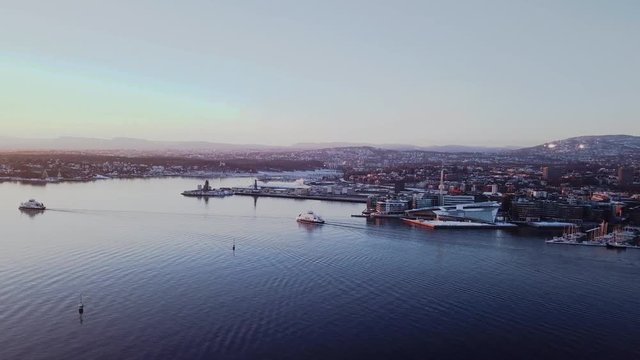 Aerial sliding shot of two ferry boats in Oslo fjord, Norway, moving towards sunset