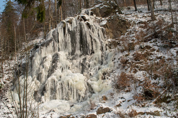 Fototapeta na wymiar Waterfall with ice in the forest