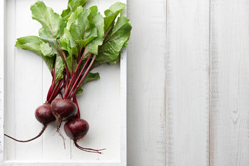 Fresh harvested beetroot in white wooden tray, top view