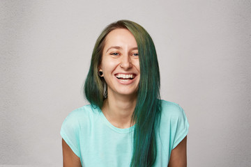 Young pretty girl with dyed green hair and pirced nose laughs because friend told a funny jocke....