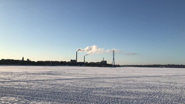 Cold nordic weather in winter time. Factory silhouette with smoke coming out from big pipes