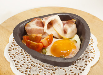 Eggs and bacon in a heart-shaped pan. The view from the top.