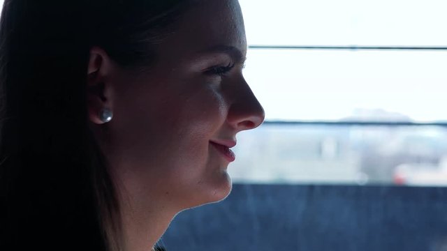 A young beautiful woman works on a smartphone in a room - face closeup from the side