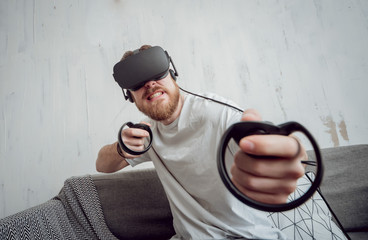 The young man playing games with virtual reality goggles
