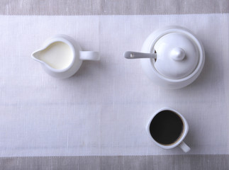 Cup of hot coffee espresso, coffee beans, jug of milk, and bowl with sugar on white background for copy space. Coffee concept.