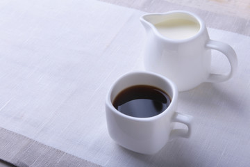 Cup of hot coffee espresso, coffee beans, jug of milk, and bowl with sugar on white background for copy space. Coffee concept.