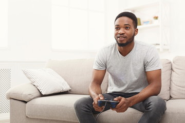 Happy young african-american man at home playing video games © Prostock-studio