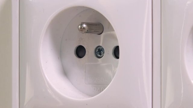 A woman unplugs a cable from a wall socket - closeup