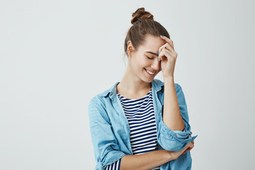 Girl enjoys her youth. Indoor portrait of good-looking urban european girl in bun hairstyle leaning...